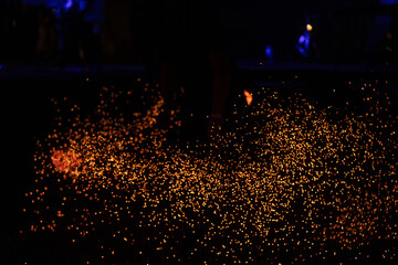 Thousands of glowing orange sparks cascade against a black background, creating a fiery and dynamic...