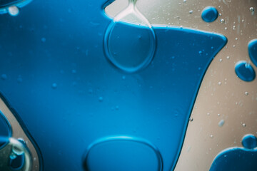 Vibrant green droplet encased in a blue fluid form, set against a neutral background with tiny...
