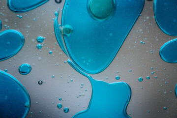 Vibrant green droplet encased in a blue fluid form, set against a neutral background with tiny...