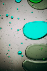 Vibrant green droplet encased in a blue fluid form, set against a neutral background with tiny...