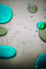 Vibrant green droplet encased in a blue fluid form, set against a neutral background with tiny...