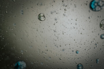 Vibrant green droplet encased in a blue fluid form, set against a neutral background with tiny...