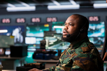 Military dispatcher using headphones microphone, offering information to commanders fighting on...