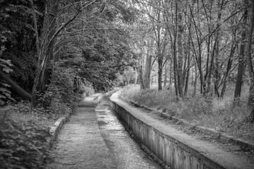 A small river in the city is enclosed in a concrete channel, flows through a beautiful park, the...