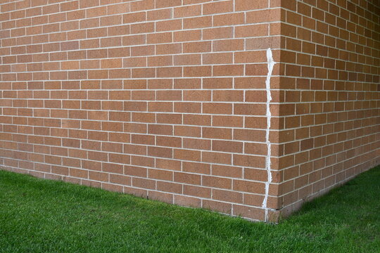 Corner of red brick building. White sealant used as a quick fix in cracked brick.