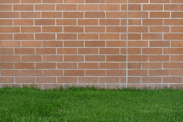Red brick wall with green grass in lower portion of frame.