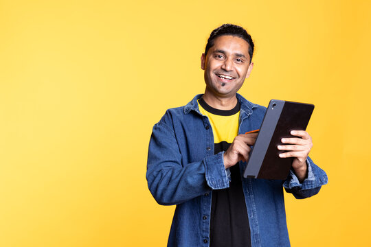 Male model smiling and accepting the payment on his mobile device, writing credit card numbers to purchase things online on websites. Young indian man processing the money transfer with the bank.