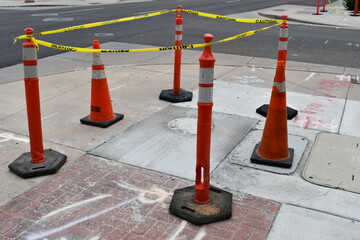 Safety cones surrounding fresh concrete in sidewalk.