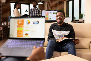 Two business professionals meet in office to share ideas and collaborate on project task. African...