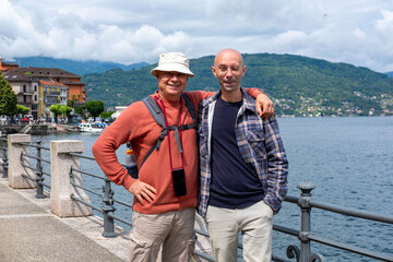 elderly, Young travelers relaxing on Baveno promenade, men enjoying Marjorie lake view, summer breeze, peaceful moment, solo trip, scenic destination