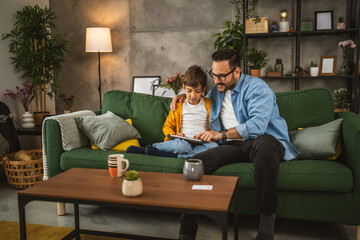 Father with eyeglasses and son use tablet for homework browse internet