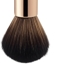 Close-up of a luxurious, professional makeup brush with a rose gold handle and soft, full bristles.