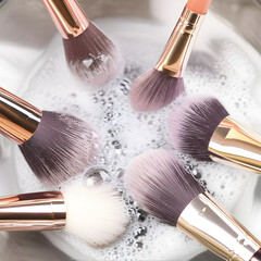 Close-up of makeup brushes soaking in soapy water, showing cleaning process.