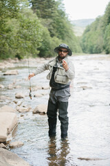 Fisherman casting line in river, enjoying trout fishing in nature