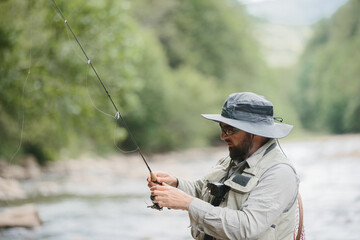 Fisherman with fishing rod catching trout in river
