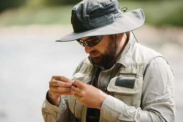 Fisherman tying fly on a fishing line, preparing for trout fishing