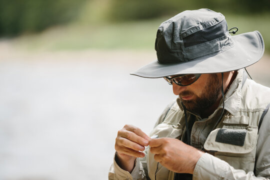 Fisherman preparing fishing tackle for trout fishing in river