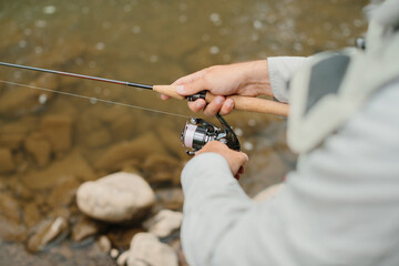 Fisherman reeling in line while fly fishing in a river