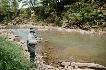 Fisherman catching trout in a mountain river: fly fishing in unspoiled nature