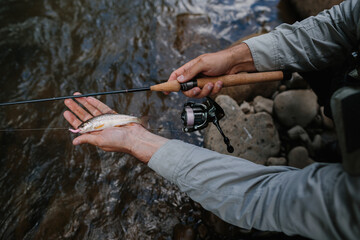Fisherman holding freshly caught trout in river