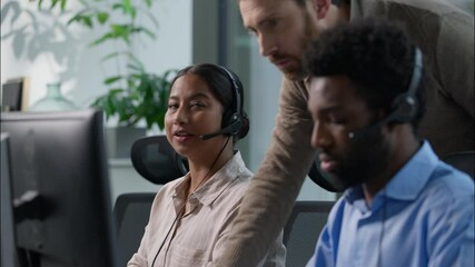 Multiethnic callcenter office teamwork Caucasian male supervisor giving instructions African call center operator headset nodding head Indian woman working computer hotline support guidance training