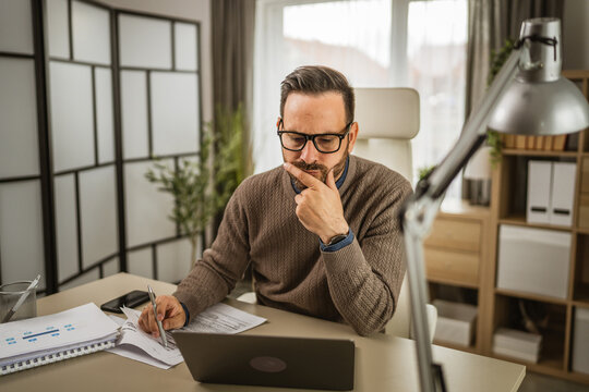 One adult man sit at office and look, read document on laptop at office