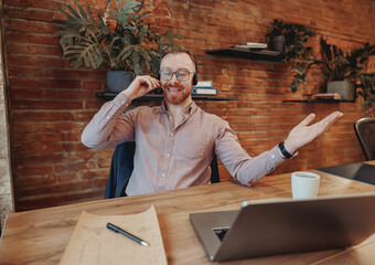 A man sitting in a stylish office environment engages in a phone call, highlighting the dynamics of...