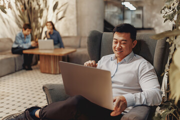 A highly focused young man diligently works on his laptop in an appealing, stylish, and relaxed...