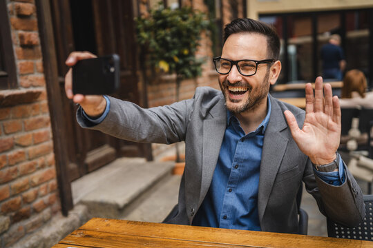 Adult man sit in cafe restaurant use cellphone for selfie video call