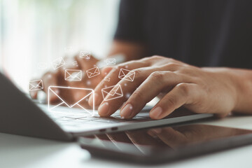 Close-up of Businessman hands typing on a laptop keyboard with floating envelope icons, sending digital mail for online communication and email marketing campaign, newsletter delivery in business list