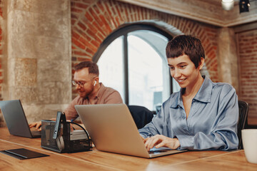 Two professionals collaborate in a coworking space, focusing on maximizing productivity effectively