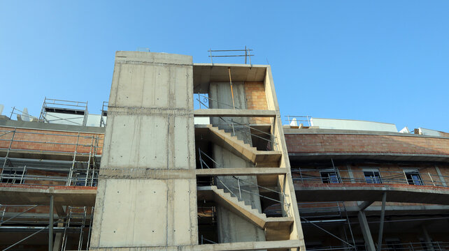 Construction activity features apartment building with scaffolding and stairwells at a development site in progress