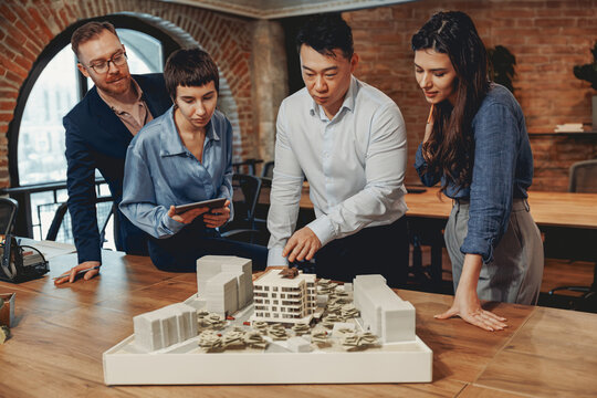 A professional team engages in a detailed discussion about an architectural model within a modern office environment