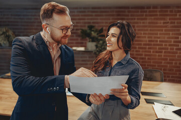 Two professionals discuss an important document in a modern office, showcasing teamwork and...