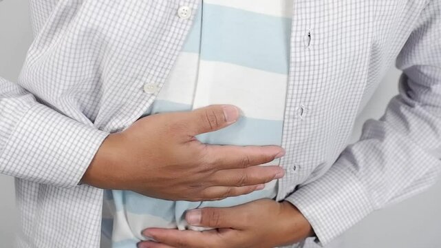 Man having pains in stomach. Young man suffering from a belly ache. Cropped shot of a sick man with an ulcer, IBS, colitis, or dyspepsia holding hands on his abdomen. Health problems concept
