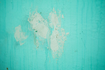 Close-up of weathered wall texture shows repairs on painted surface, creating an abstract pattern....