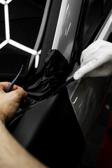 Vinyl wrap installation on car with precise edge trimming near windshield area. Vinyl wrap...