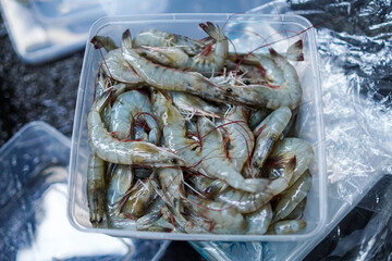 A container filled with fresh raw shrimp, ready to be cooked and enjoyed. The shrimp are plump and...