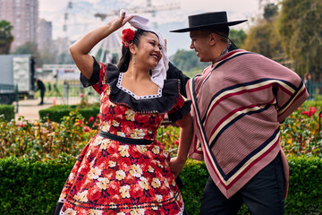 Portrait of a smiling young couple, dressed as Chilean huasos, looking at each other and posing...