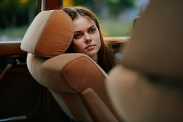 Pensive young woman leaning on car seat, lost in thought, capturing the essence of nostalgia and tranquility in natural light.