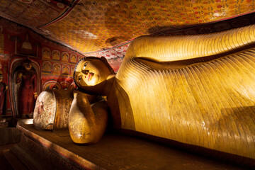 Interior of Dambulla Cave Temple, Sri Lanka, with ancient Buddha statues and mural-covered stone walls. Travel and history.