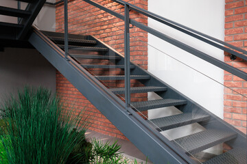 Modern metal staircase with glass railing and brick wall background Industrial design with natural...