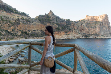 MUJER JOVEN MORENA MIRANDO AL MAR DESDE  playa paradisíaca cala del moraig turismo españa verano...