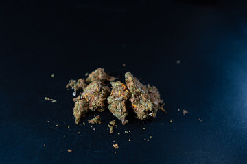 Cannabis buds are displayed on a dark surface. Selective focus