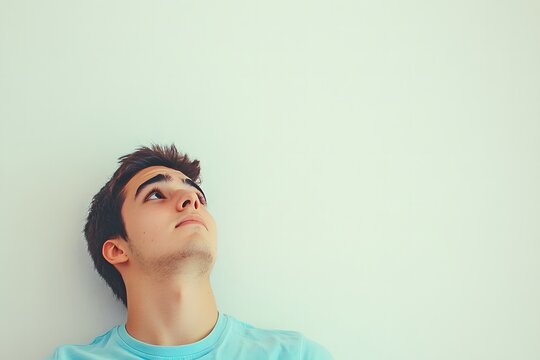 Young Man Looking Upward with Thoughtful Expression Against Plain Background - Powered by Adobe