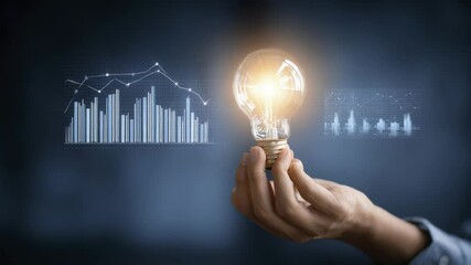 Hand Holding Lightbulb Against Digital Graphs with Business Growth Concept - Powered by Adobe