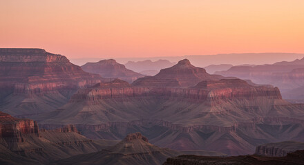 Naklejka premium Layered hills at sunset, warm light with pink haze in background