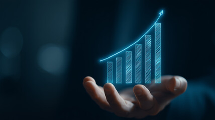 A business hand reveals a rising bar chart hologram signifying financial growth analytics and strategic success.
