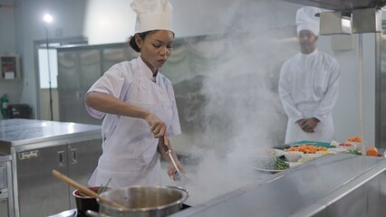 Female chef cooking with a pan in the kitchen, chef preparing food