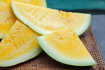 Pieces of ripe yellow watermelon on table near swimming pool, closeup